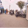 Motociclette parcheggiate vicino all'ingresso di un'area turistica con persone in costume da bagno.