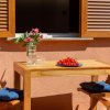 Tavolo di legno con piatto di pomodori, due sedie e vaso di fiori, davanti a una finestra.