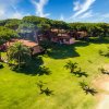 Bungalow immersi in un prato verde con alberi alti e spiaggia sabbiosa vicino.
