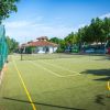 Campo da tennis all'aperto con recinzione verde.