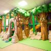 Area giochi al coperto con alberi finti e percorsi.
