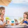 Famiglia pranza all'aperto con vista sul mare.