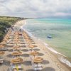 Spiaggia con ombrelloni di paglia e mare blu.