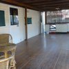 Veranda in legno con sedie e tavolo in rattan, cucina esterna sullo sfondo.