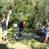 Persone fanno tiro con l'arco in un bosco, seguiti da un istruttore.