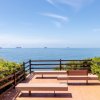 Panchine su terrazza con vista mare e navi in lontananza.