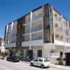 Edificio moderno con auto parcheggiate davanti.