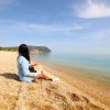 Persona seduta su una spiaggia di ciottoli.