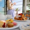 Tavola apparecchiata con dolci e tè, persona sullo sfondo.