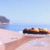 Piattino di dolci tenuto davanti alla spiaggia.