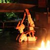 Esibizione acrobatica notturna con due persone che formano una piramide umana vicino al fuoco.