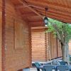 Chalet in legno con veranda, tavolo e sedie da esterno sotto un tetto inclinato.