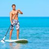 Uomo in piedi su una tavola da paddle in mare.