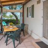 Veranda con tavolo apparecchiato e sedie verdi.