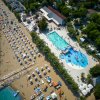 Piscina accanto a una spiaggia affollata con ombrelloni.